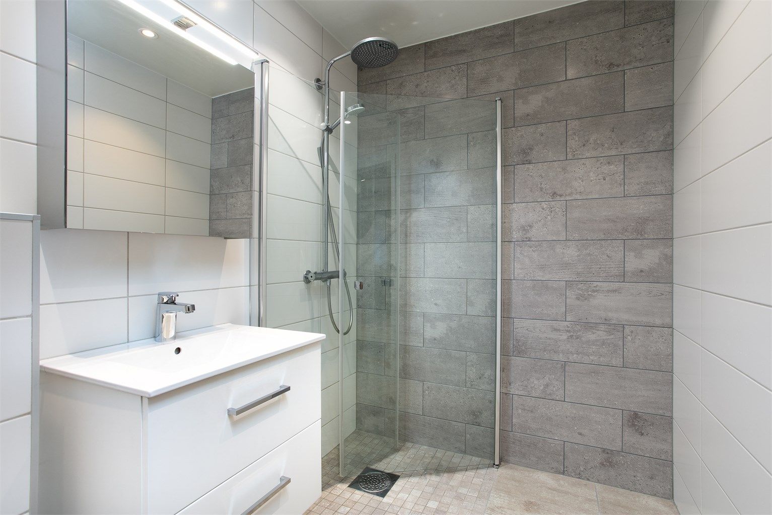 Dusjhjørne med innfellbare glassdører og moderne regnfallsdusj.