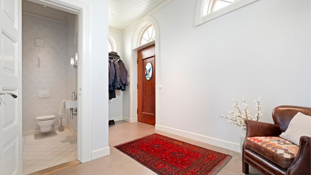 Entréen har en elegant hovedytterdør i teak og et originalt vindu med farget glass