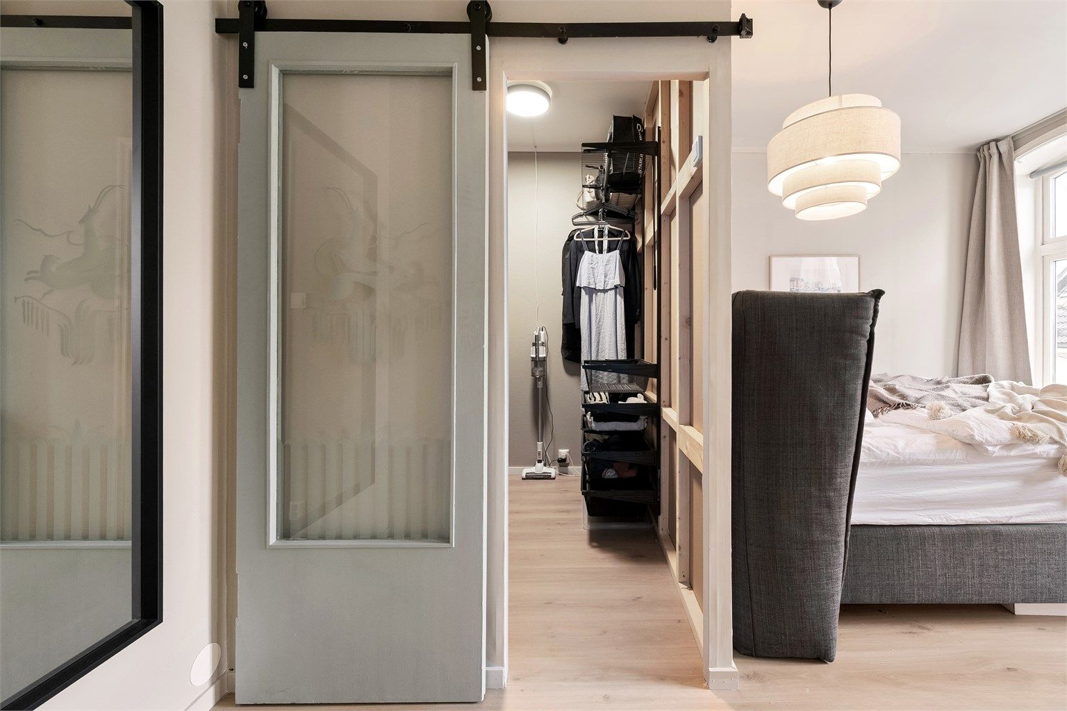 En skyvedør med glassfelt leder inn til et praktisk walk-in-closet.