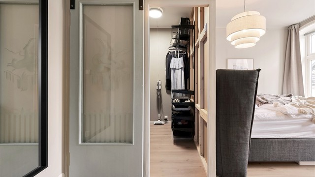 En skyvedør med glassfelt leder inn til et praktisk walk-in-closet.