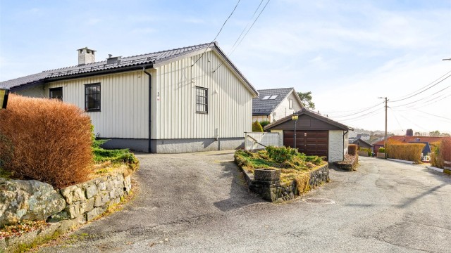 Asfaltert oppkjørsel med biloppstillingsplass og garasje.