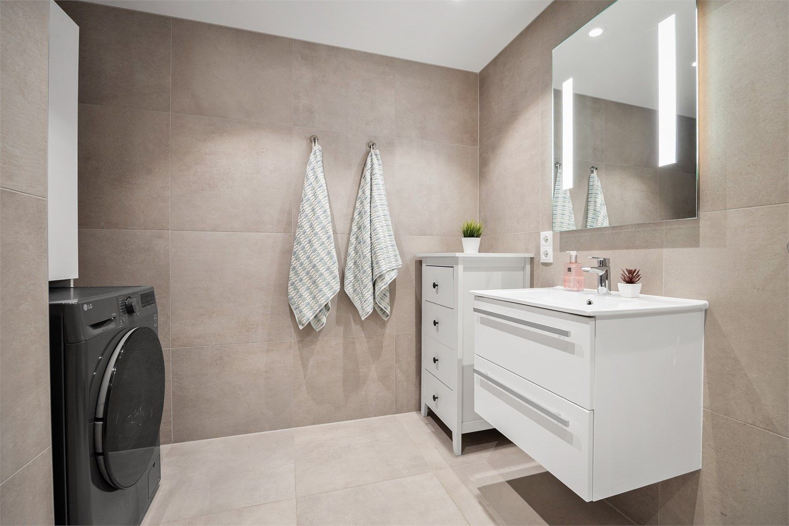 Badet har downlights i tak, varmekabler og opplegg for vaskemaskin.