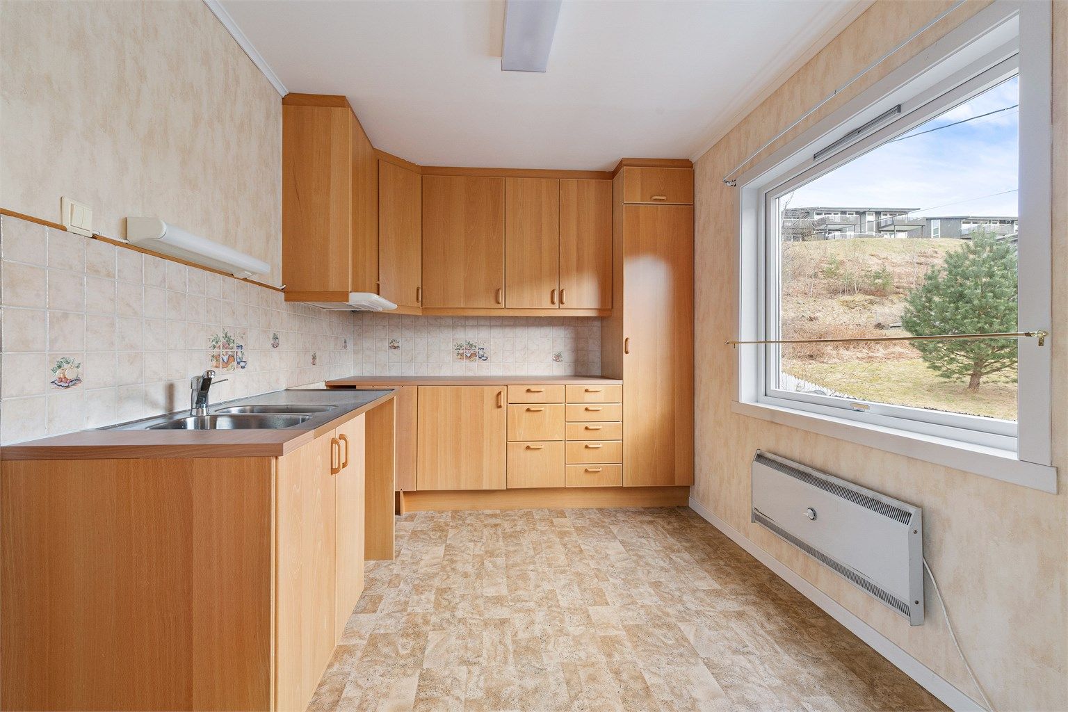 Kjøkkenet i første etasje har en innredning med finerfronter, trolig fra 1980-tallet