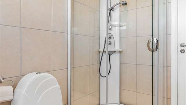 Badet har vegghengt servantinnredning med ovenpåliggende servant med armatur og speilskap med overlys. Dusjkabinett med dusjarmatur og gulvstående toalett.