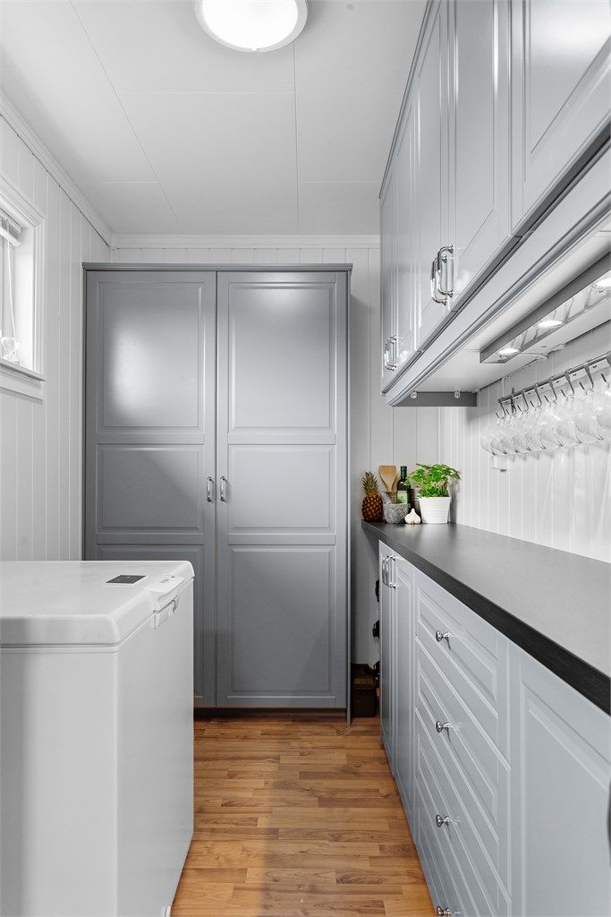 Praktisk matbod med innredning med profilerte fronter. Rommet har god plass til oppbevaring av tørrvarer og kjøkkenredskap. Krokoppheng på vegg over benken følger ikke med.