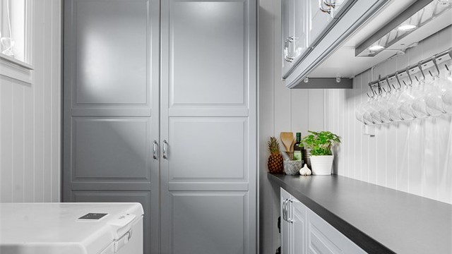 Praktisk matbod med innredning med profilerte fronter. Rommet har god plass til oppbevaring av tørrvarer og kjøkkenredskap. Krokoppheng på vegg over benken følger ikke med.