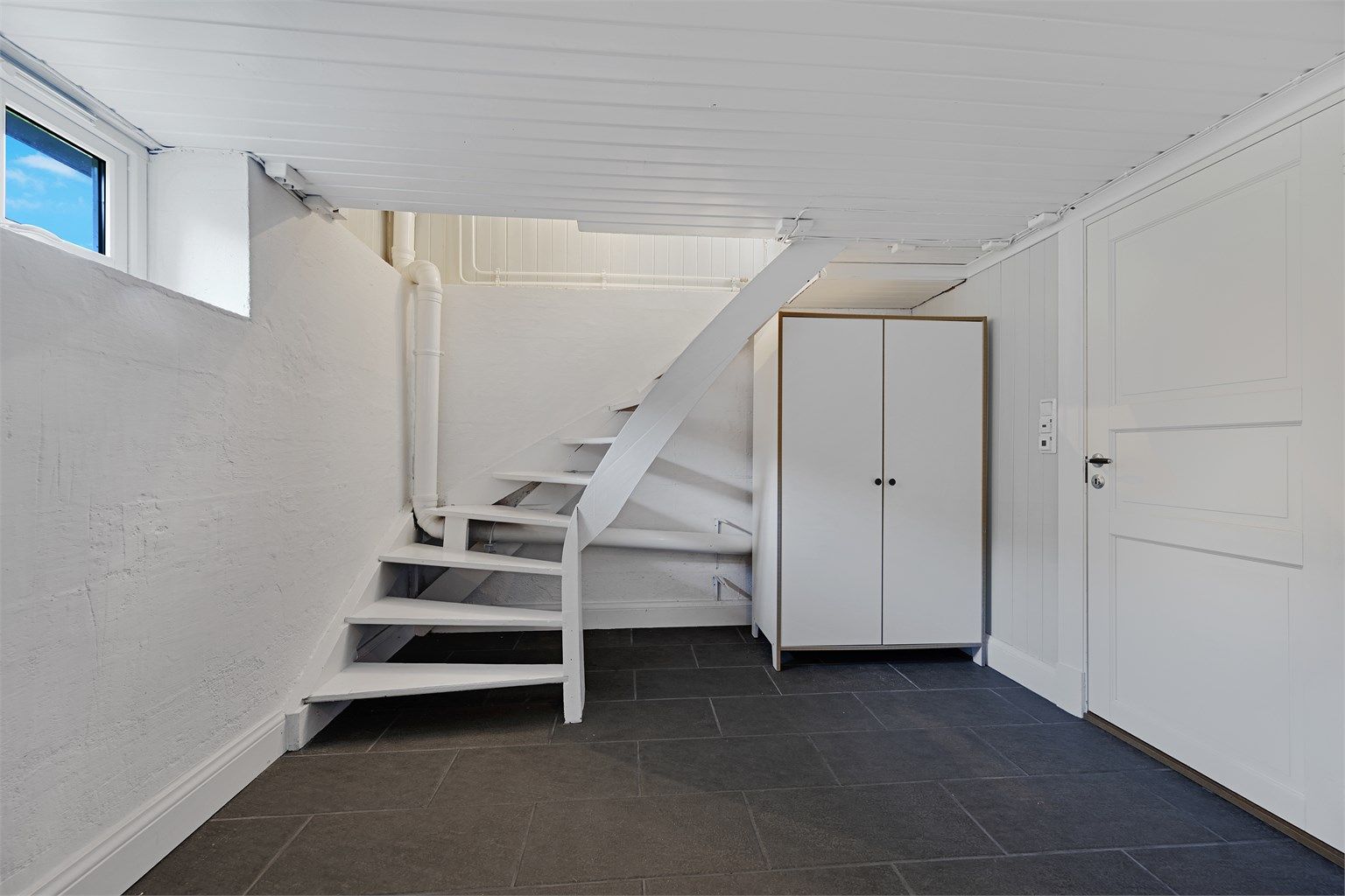 I kjelleren er det trapperom, bad/vaskerom, soverom, soverom/trimrom, kott og bod. Kjelleretasjen er ikke omsøkt fra tilleggsdel til hoveddel, samt at takhøyden er lavere en dagens krav til takhøyde for rom til varig opphold. 