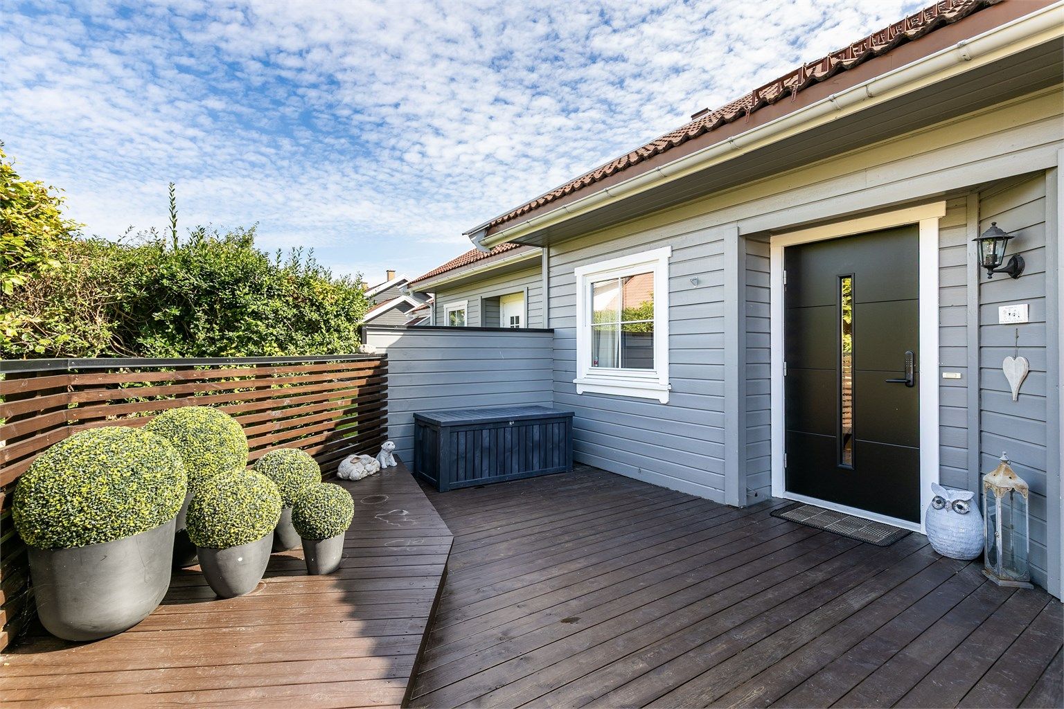 På inngangssidens tilbaketrukne terrasse kan du sitte ute i usjenerte og skjermede omgivelser. 