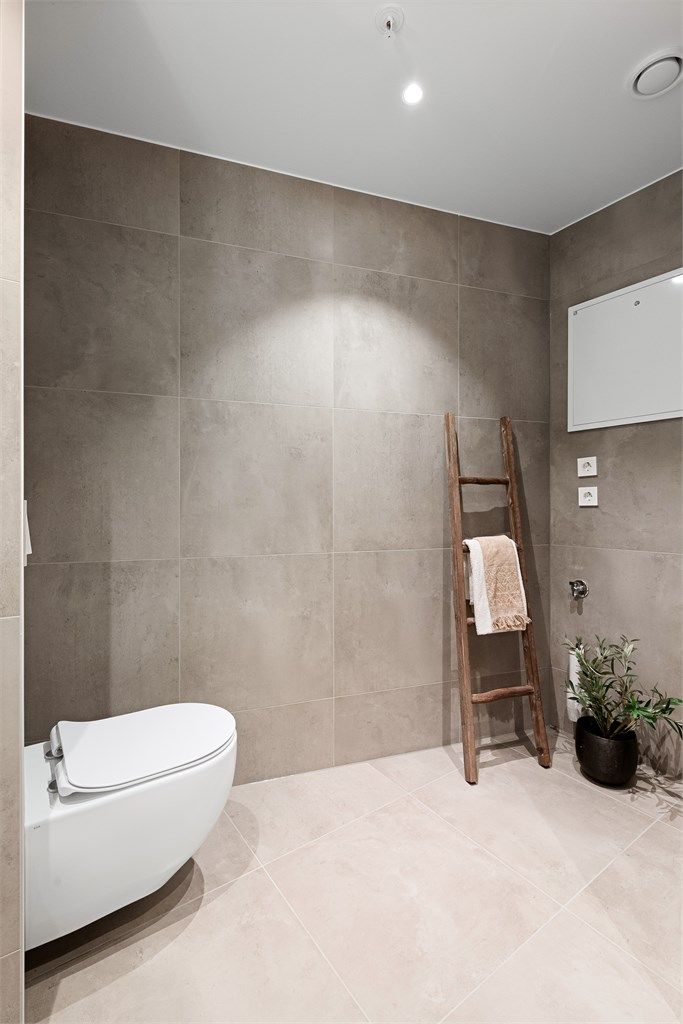 Badet er utstyrt med vegghengt toalett for et stilrent uttrykk og enklere renhold. Opplegg for vaskemaskin og tørketrommel.