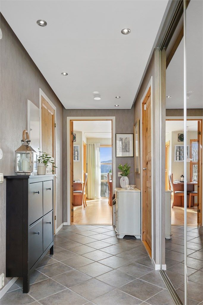 Entréen har flislagt gulv og en stor skyvedørsgarderobe i speil med god oppbevaring.