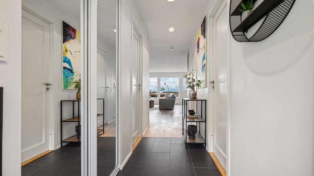 Flislagt entré/gang med varmekabler i gulv og skyvedørsgarderobe med speilfronter. Downlights i tak. Ved entré ligger begge soverom på hver sin side.