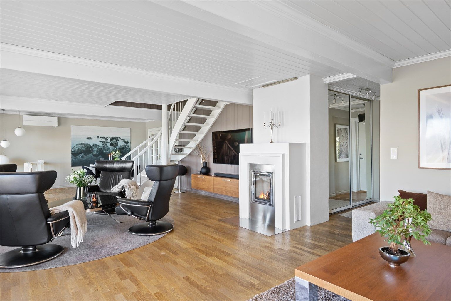 Stuen har varmepumpe fra 2023, samt hygge fra en stilig, innfelt peis med glassdør og ramme i stål.