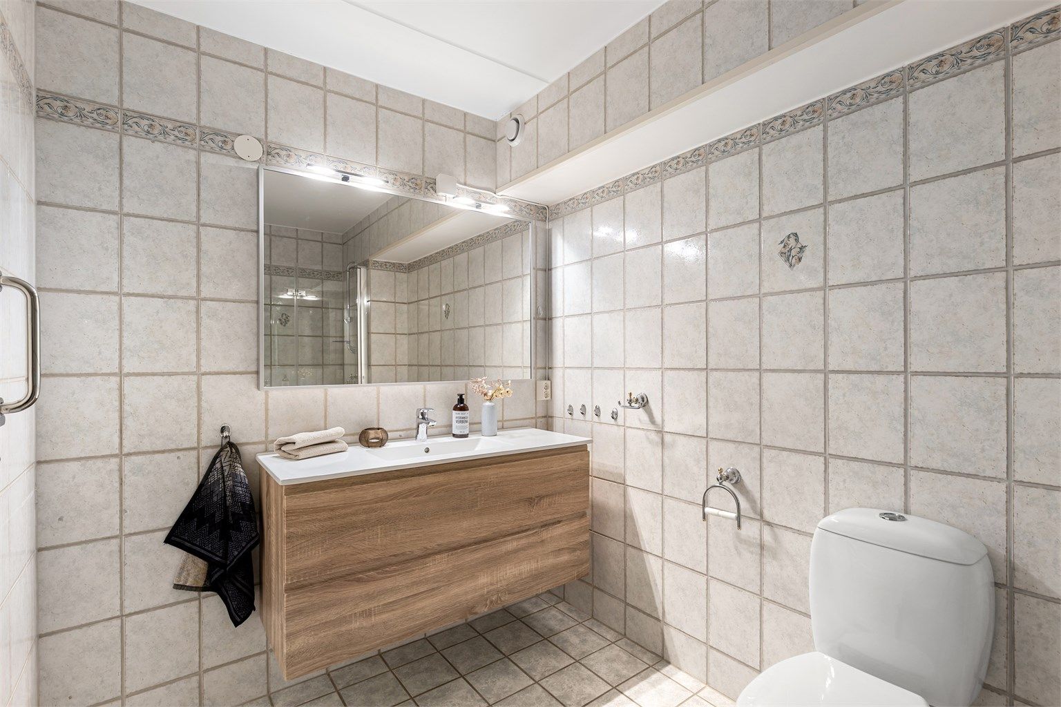 Vegger og gulv er flislagt med gulvvarme, badet er videre utstyrt med gulvstående WC, dusj og stort servantmøbel med speil med belysning. 