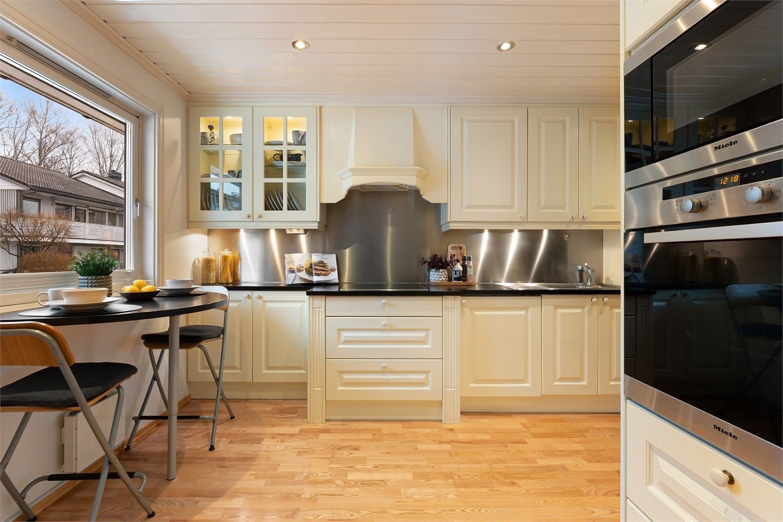 Innredningen har profilerte fronter, benkeplate i tre og en praktisk, liten spiseplass ved vinduet.