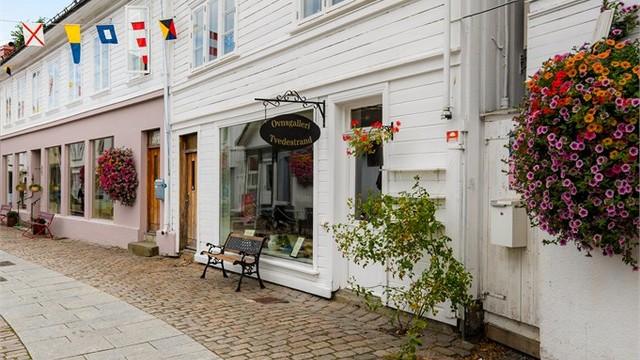 Midt i hjertet av Tvedestrand - Brosteinsbelagte gate med butikker og cafeèr rett utenfor døren.