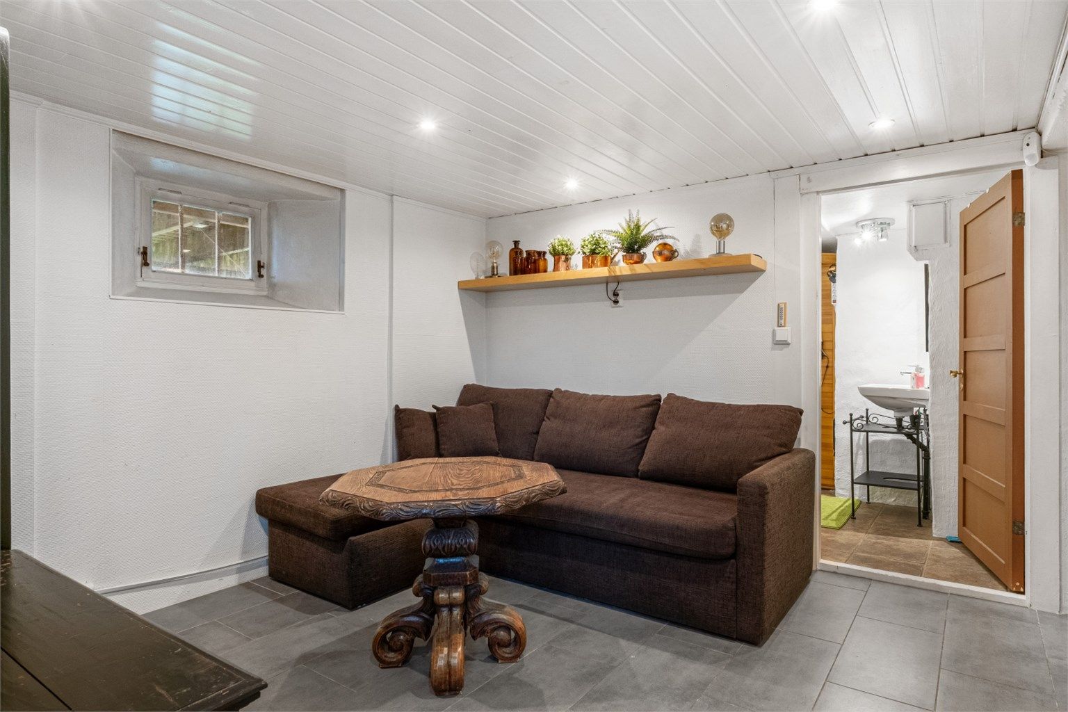 Rommet er innredet med gulvfliser med varme og downlights i himling