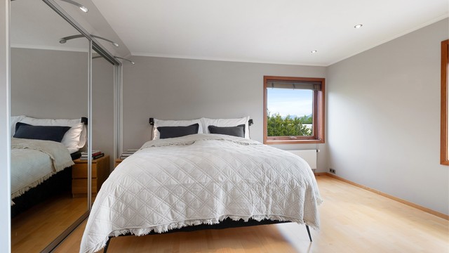 Soverom med stor skyvedørsgarderobe med speilfronter og god plass til dobbeltseng.