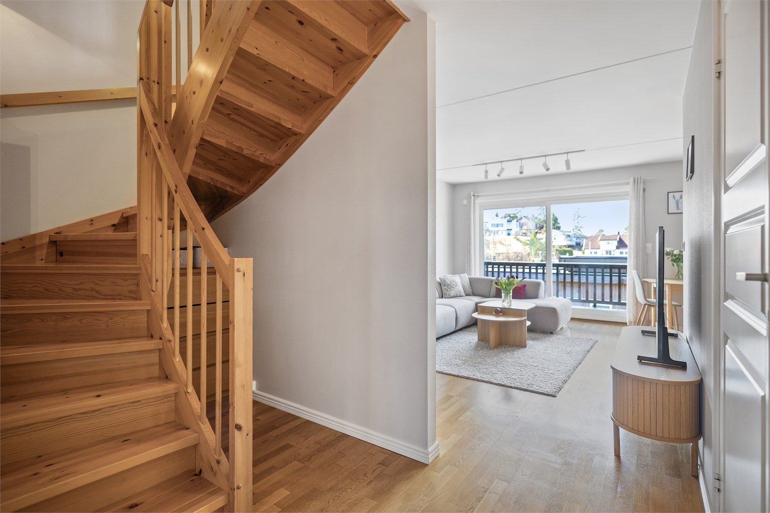 Inngangspartiet glir naturlig over i stuen, der eikeparkett og malte, glatte veggflater danner en klassisk og tidløs ramme. 