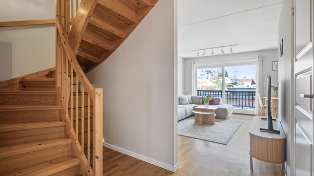 Inngangspartiet glir naturlig over i stuen, der eikeparkett og malte, glatte veggflater danner en klassisk og tidløs ramme.