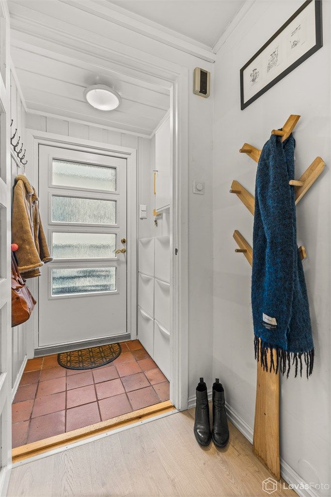 Du ønskes velkommen inn i en entré med slitesterkt flisgulv og malt trepanel.