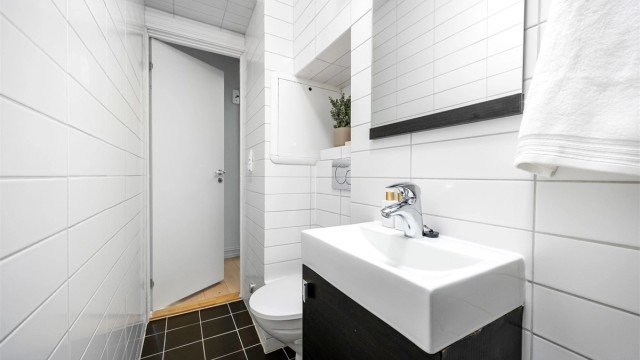 Videre er det vegghengt toalett med innebygget sisterne og praktisk nisje for ekstra oppbevaring.