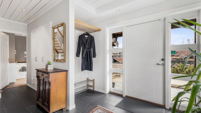 Romslig, flislagt entré med plass til oppbevaring av ytterklær og sko.