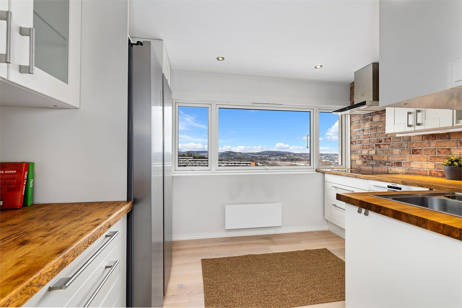 Kjøkkeninnredning fra 2010 med profilerte fronter, benkeplate i tre og en karakterfull teglsteinsvegg. Alle hvitevarer medfølger.