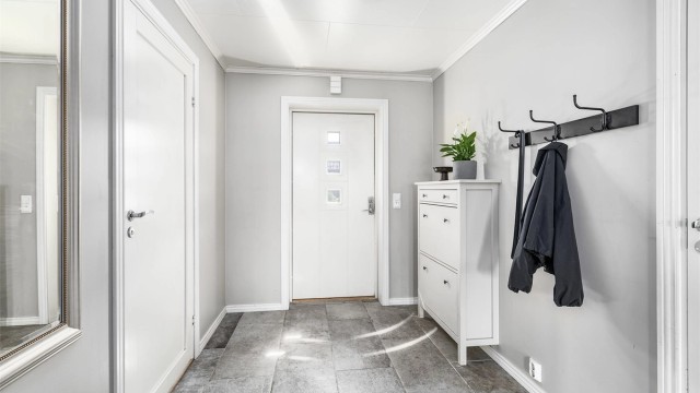 Entreens gulv er utført med en robust og praktisk overflate av fliser. I gulvet er det også varmekabler.