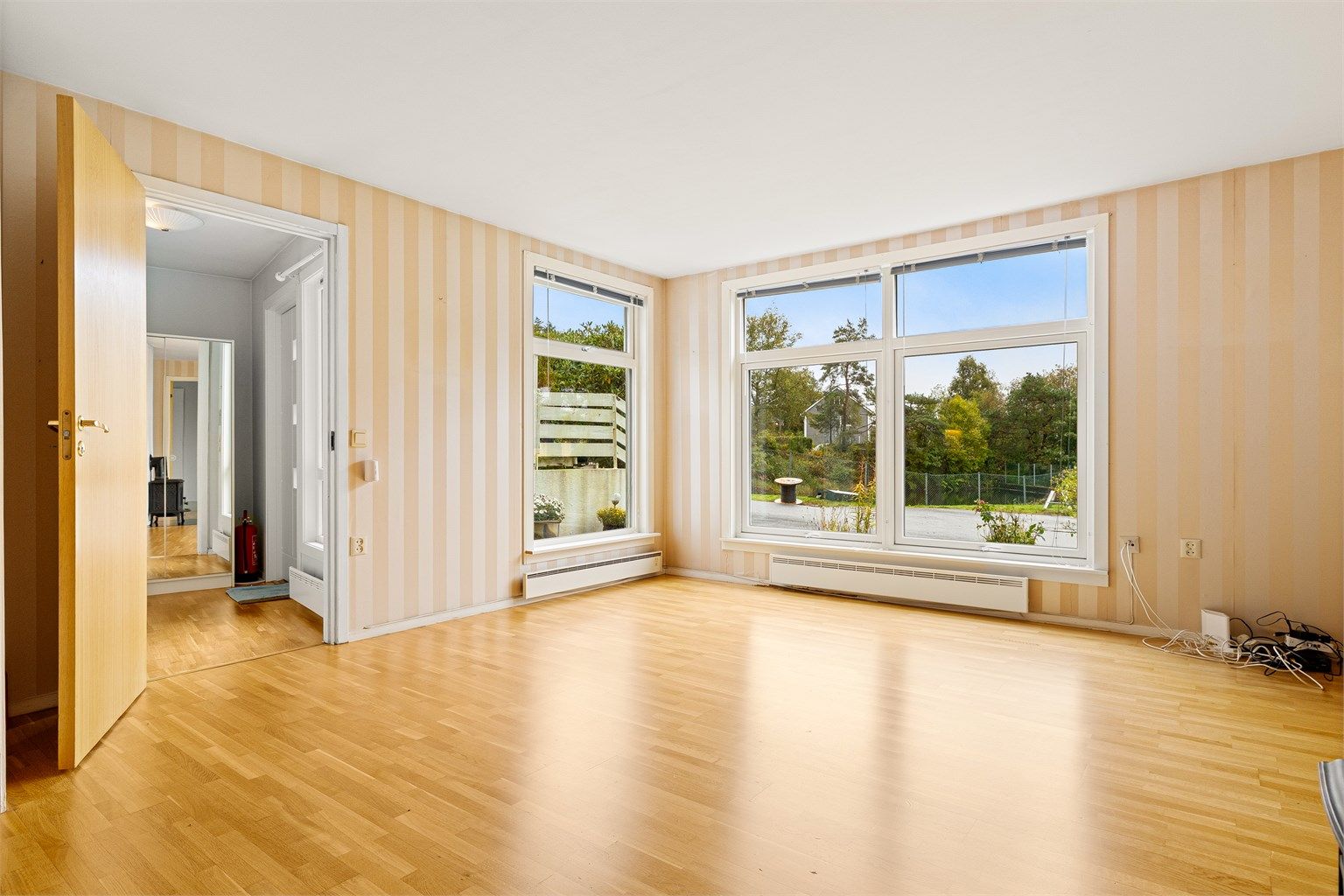 Lys stue med parkett på gulv og vinduer fra 2019.