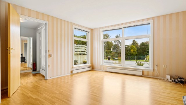 Lys stue med parkett på gulv og vinduer fra 2019.