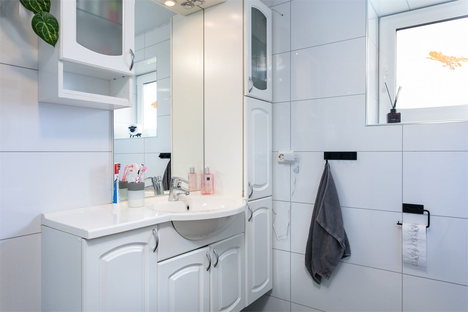 Bad i underetasjen med flislagt gulv med varmekabler, flislagte vegger og malt tak.