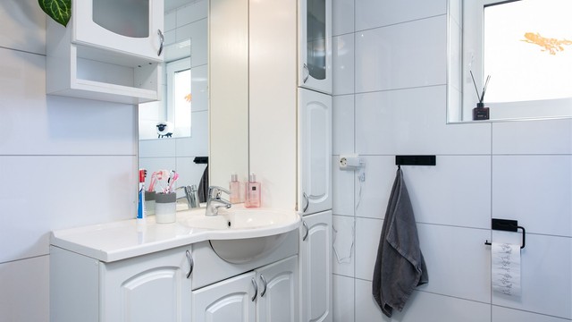 Bad i underetasjen med flislagt gulv med varmekabler, flislagte vegger og malt tak.