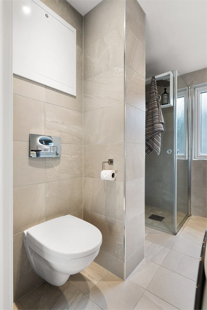 Badet er flislagt, har vegghengt toalett og foldbare dusjdører.