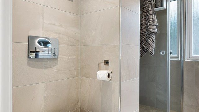 Badet er flislagt, har vegghengt toalett og foldbare dusjdører.