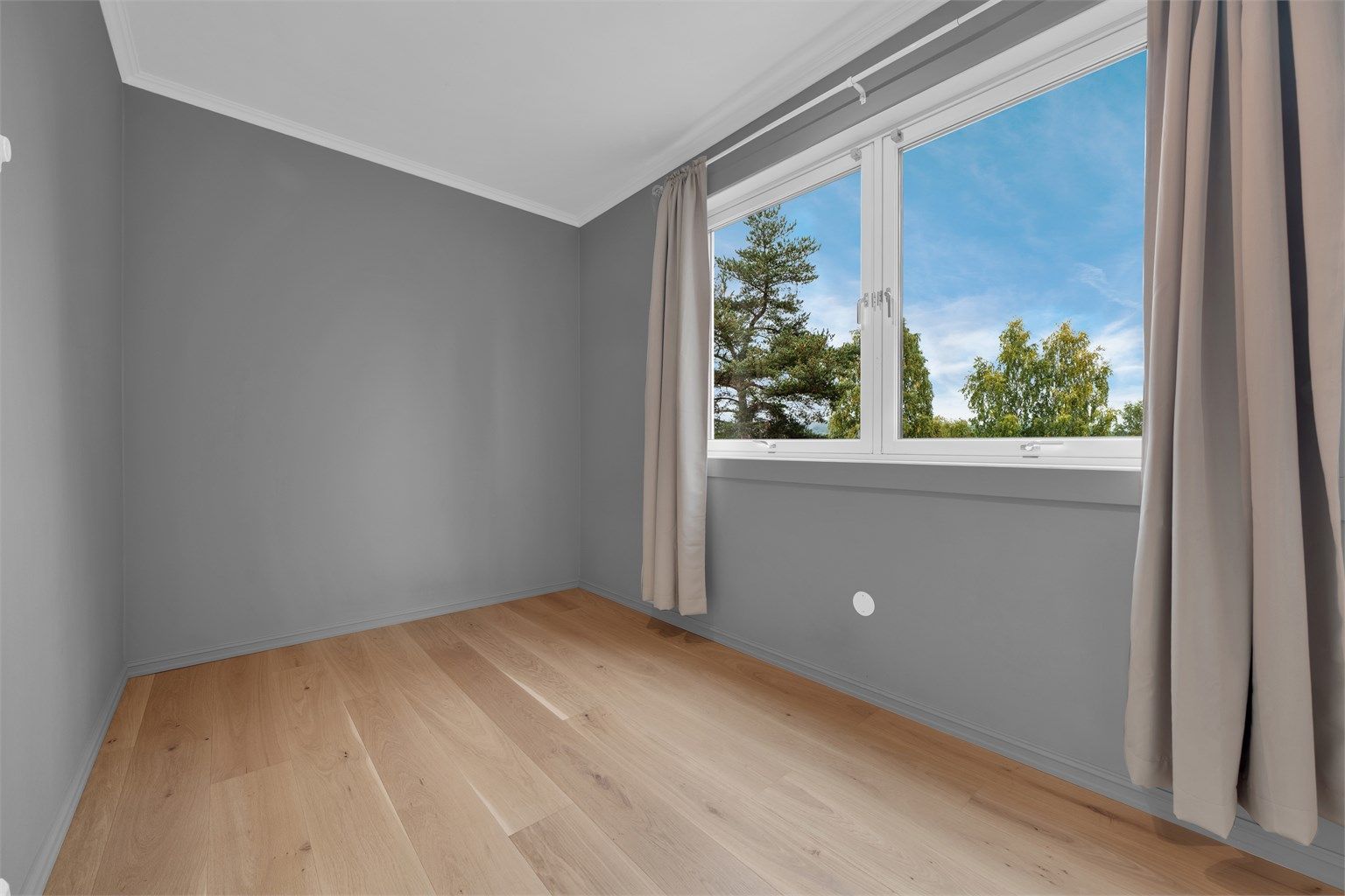 God plass til seng og skrivebord, med store vindusflater som slipper inn rikelig med dagslys.