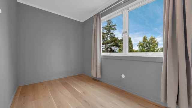 God plass til seng og skrivebord, med store vindusflater som slipper inn rikelig med dagslys.