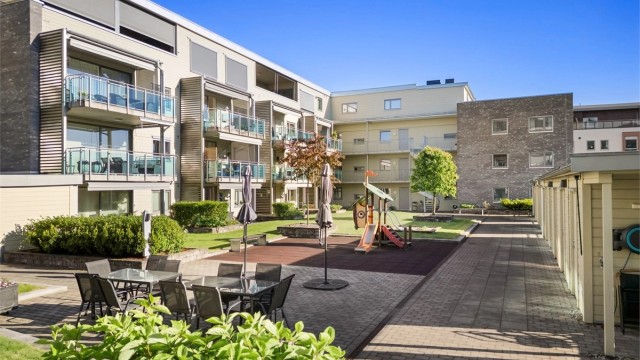 Pent opparbeidet felles atrium beliggende i byggets 2. etasje med utemøbler og parasoller