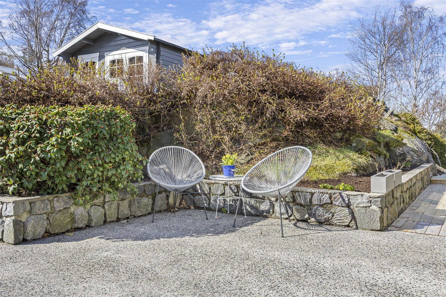 Tomten er pent opparbeidet med forstøtningsmurer i betong, plen og beplantning.