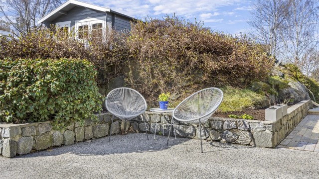 Tomten er pent opparbeidet med forstøtningsmurer i betong, plen og beplantning.