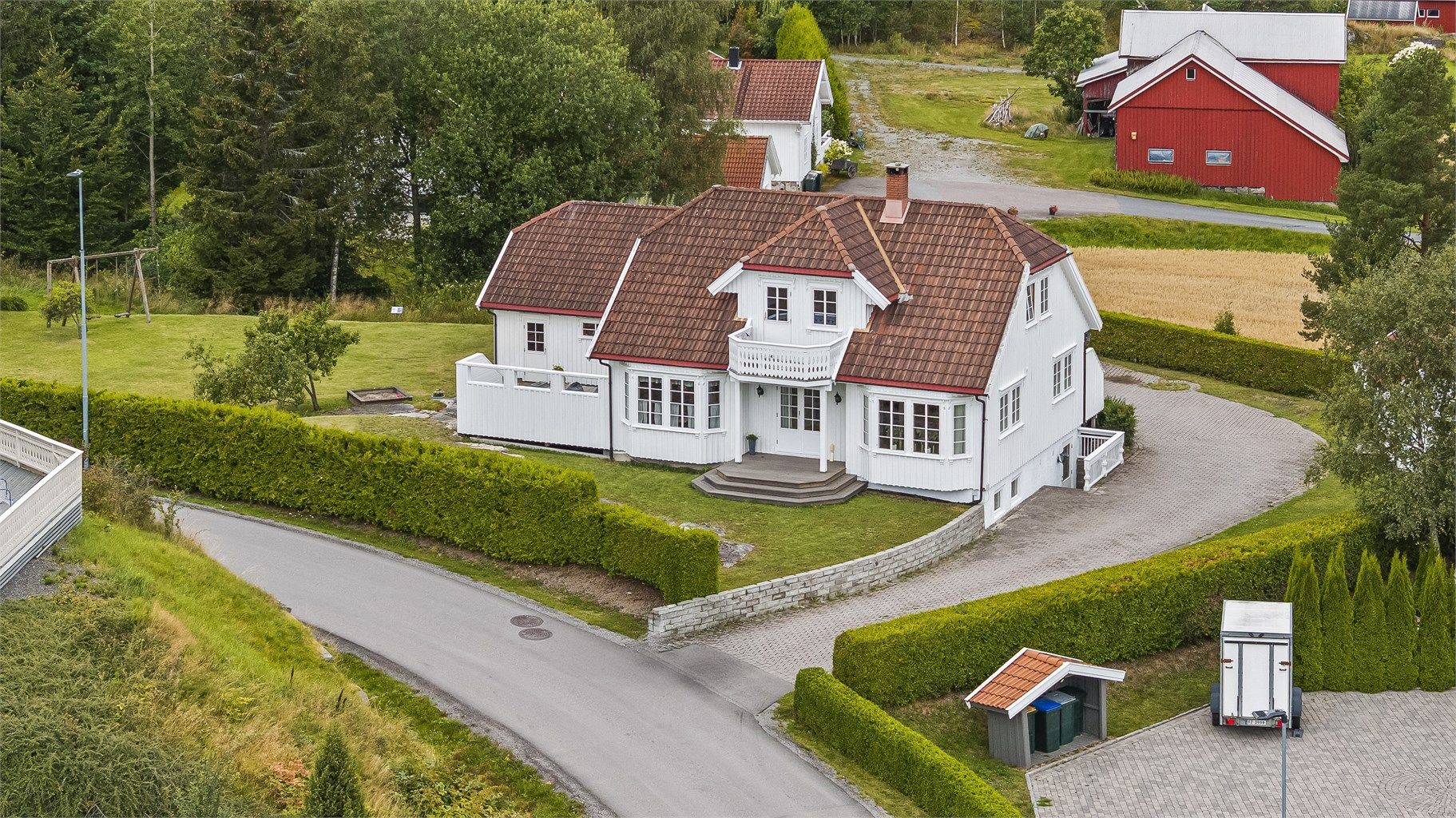 Innkjørselen er belagt med belegningsstein og hekk ut mot veien for å skjerme tomten
.
