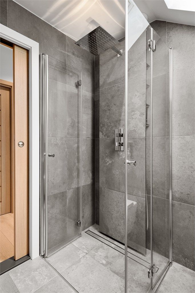 Dusjhjørne med innfellbare glassdører og regnfallsdusj. Rør-i-rør-systemet har fordelerskap plassert på badet.