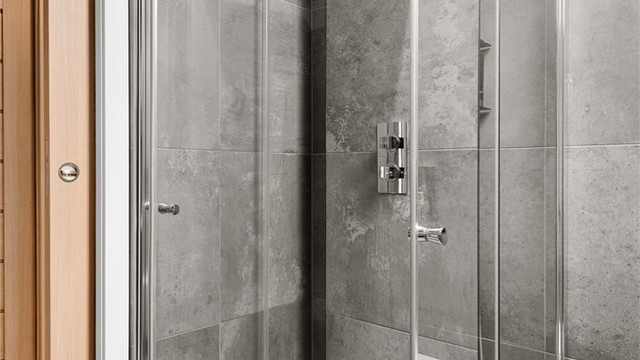 Dusjhjørne med innfellbare glassdører og regnfallsdusj. Rør-i-rør-systemet har fordelerskap plassert på badet.