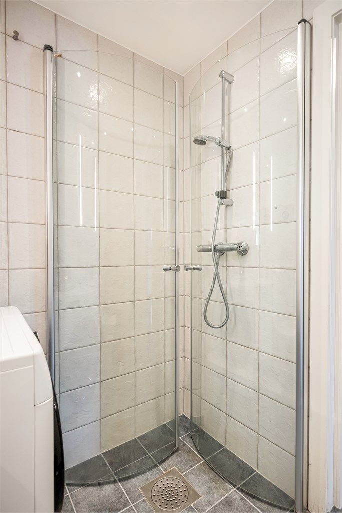 Svingbare glassdører gir et luftig inntrykk, mens mønstrede gulvfliser gir badet et fint særpreg.