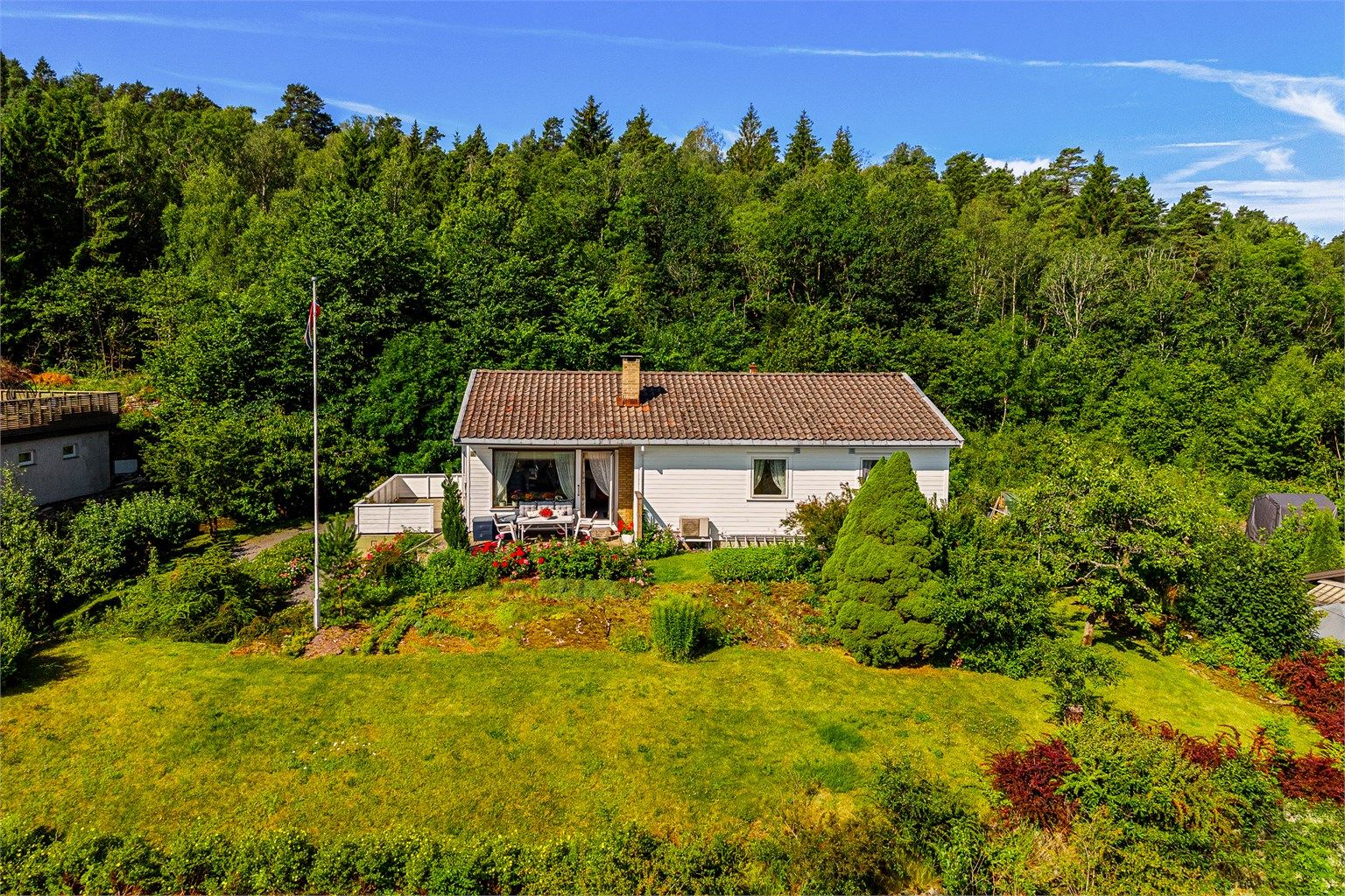 Hagen er pent opparbeidet og beplantet med blomsterbed, frukttrær, bær- og prydbusker.