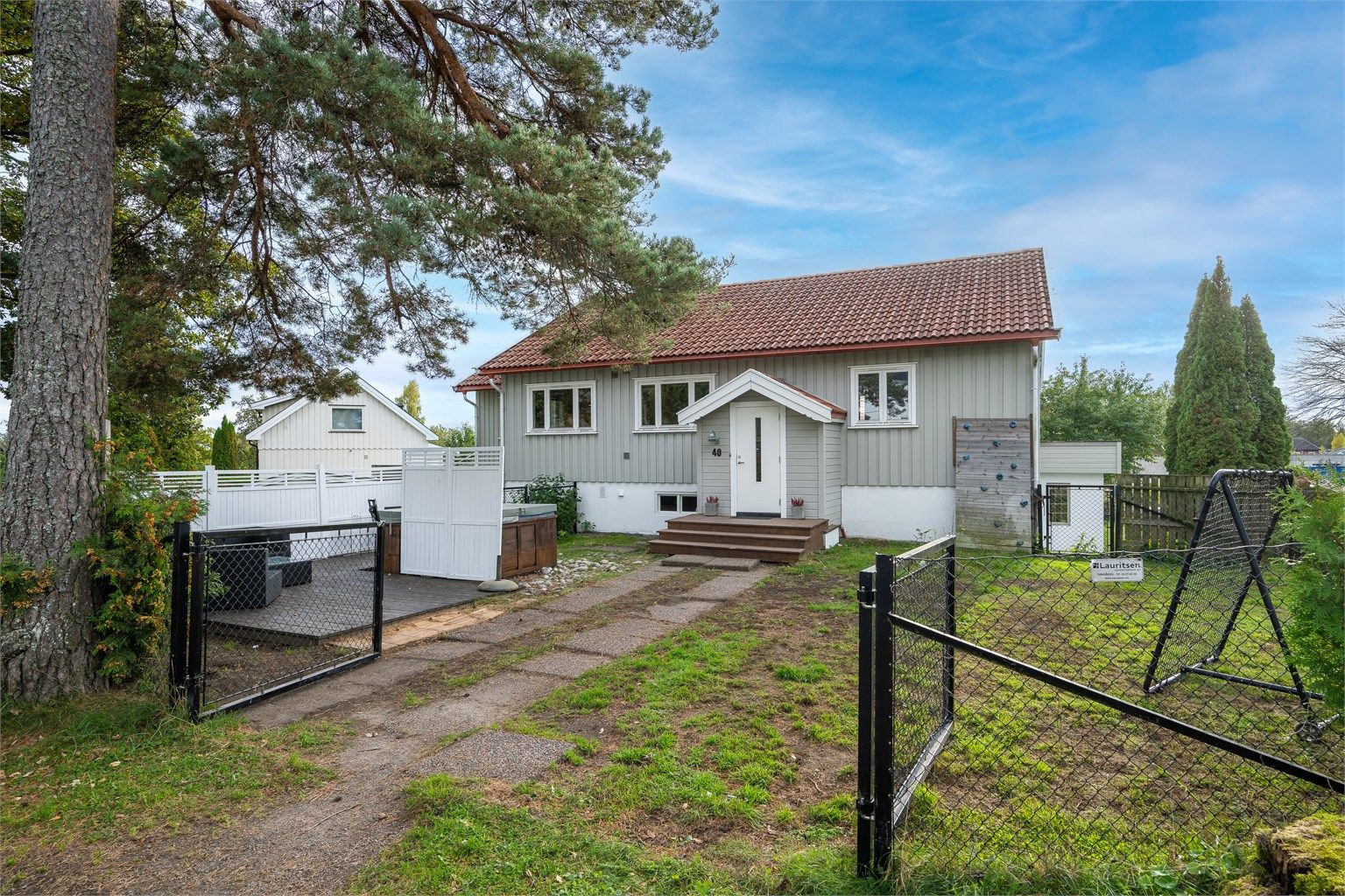 Inngjerdet med inngangsparti, gressplen og markterrasse med boblebad