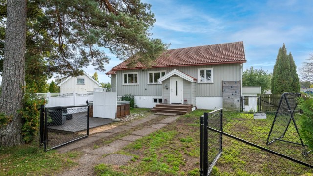 Inngjerdet med inngangsparti, gressplen og markterrasse med boblebad