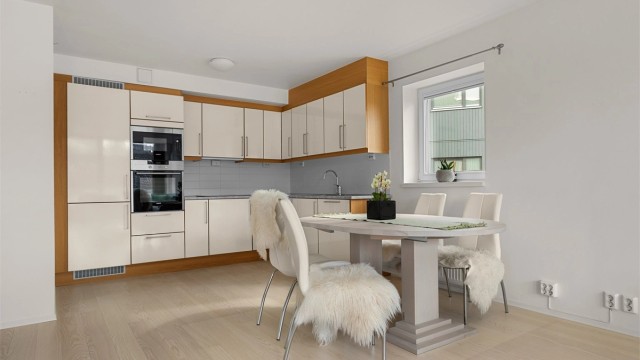 Kjøkkenet ligger naturlig tilbaketrukket fra stuen og er innredet med lyse slette fronter og benkeplate med laminert overflate.