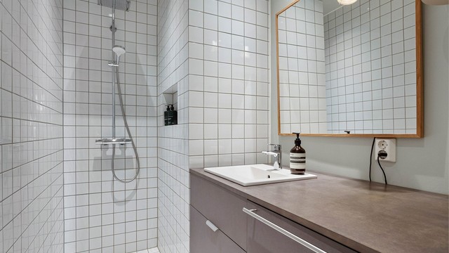 Baderom ble totalrenovert i 2021 og har en tidløs materialpalett med fliser, gulvvarme og en romslig dusjsone.