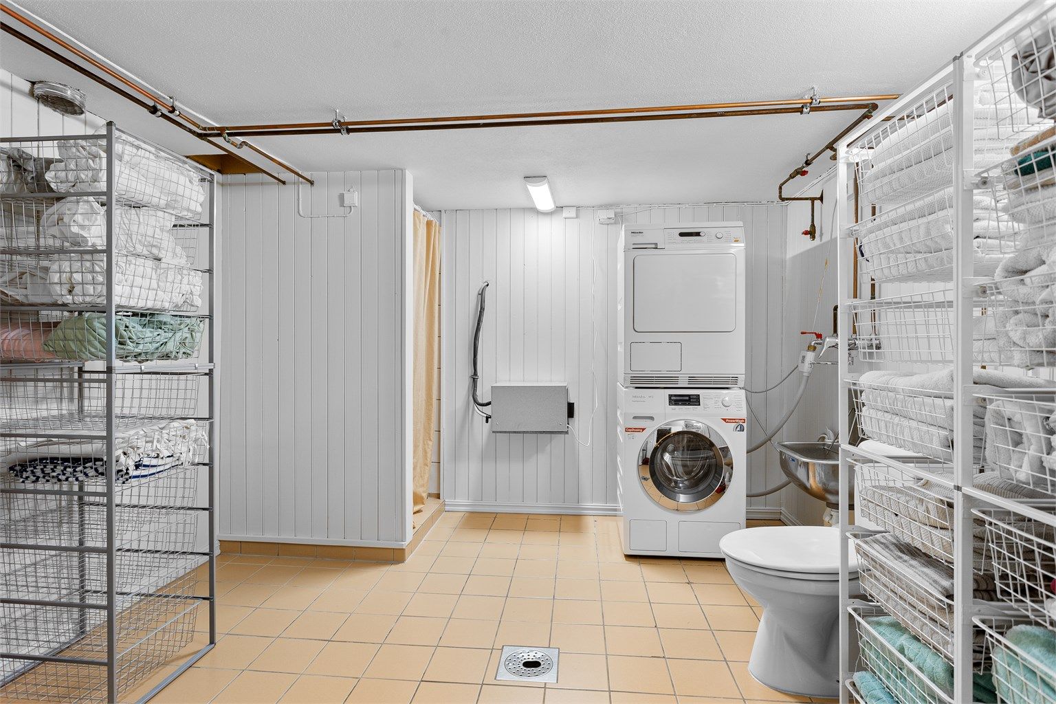 Vaskerom med flislagt gulv med varme i kjelleretasjen. Innredet med vegghengt utslagsvask. Dusjhjørne med forheng og gulvstående toalett. Opplegg for vaskemaskin.