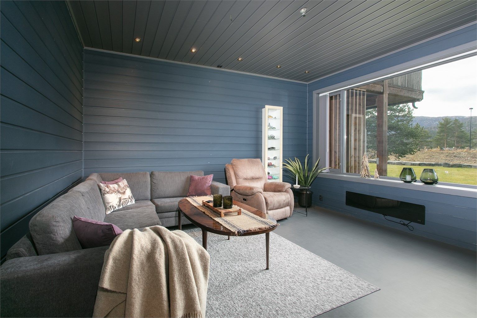 Stuen har god plass til stor sofagruppe og store vindusflater mot naturen utenfor.